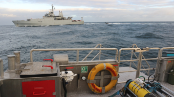 A submarine glider ready for deployment (front right) with HMS Enterprise in the background (Photo: NOC)
